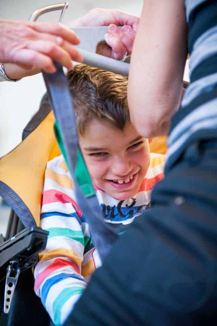 Joel får hjälp att komma upp i den specialbyggda elrullstolen. Foto: Anna Pella.